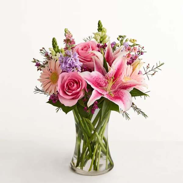 Pink roses and lilies arranged in a clear glass vase