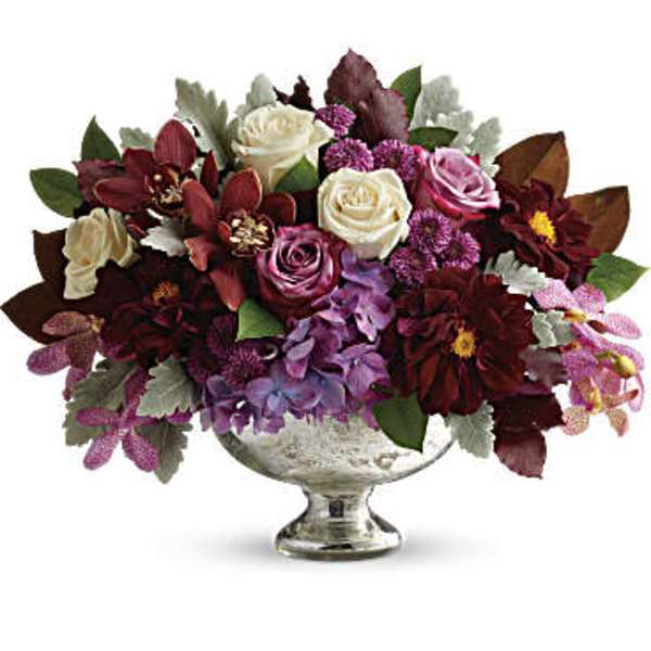 Mixed bouquet of roses and purple flowers in a silver pedestal vase