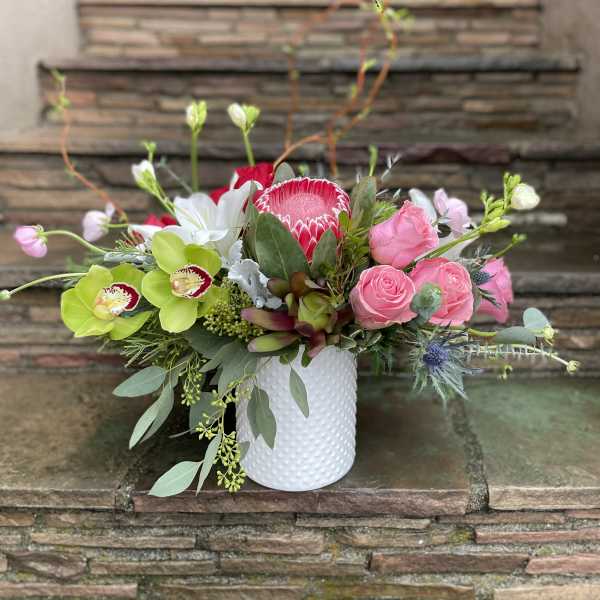 Pink roses and orchids arranged in a white textured vase