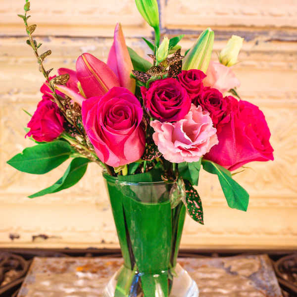 Pink roses and lilies arranged in a clear glass vase