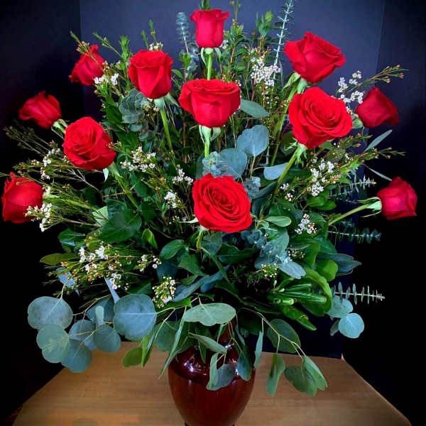 Tall bouquet of red roses in a dark vase