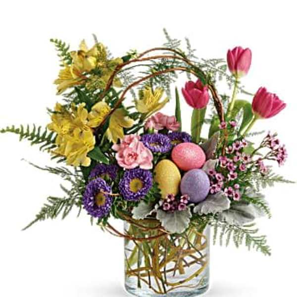 Colorful spring bouquet in a clear glass vase with decorative eggs