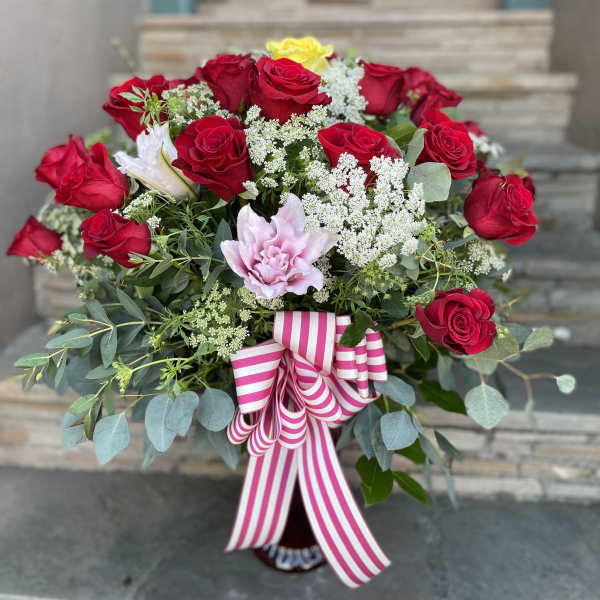 Bouquet of red roses with pink and yellow blooms and a striped ribbon