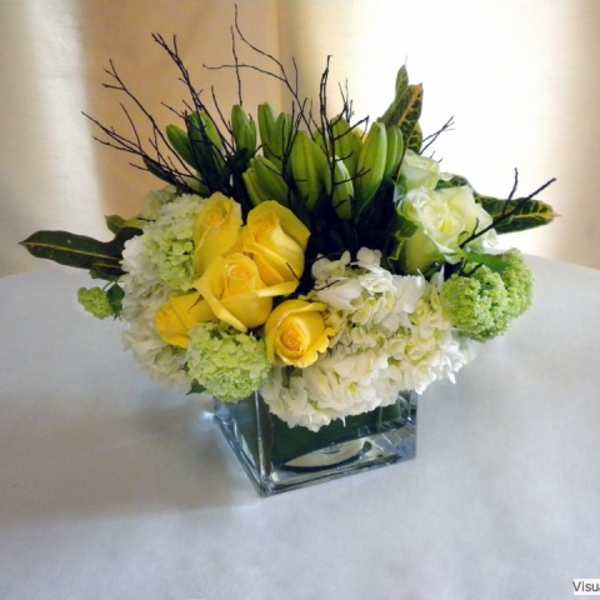 Yellow roses and white flowers in a square glass vase