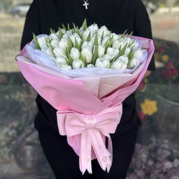Bouquet of white tulips wrapped in pink paper with a bow