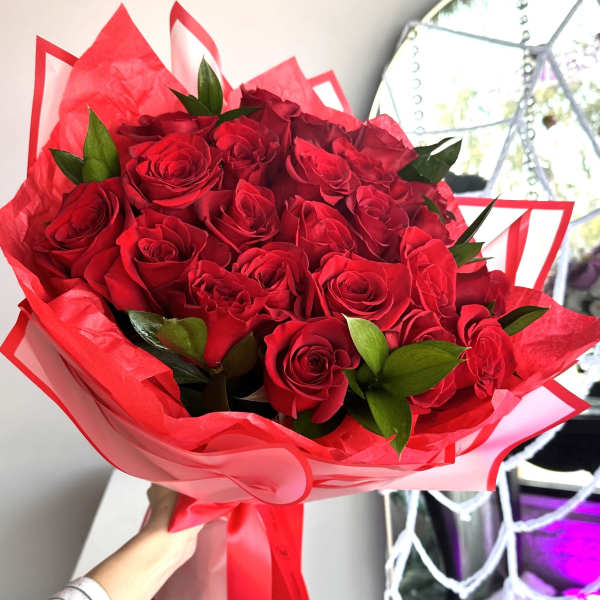 Hand-tied bouquet of red roses wrapped in red paper with a matching ribbon