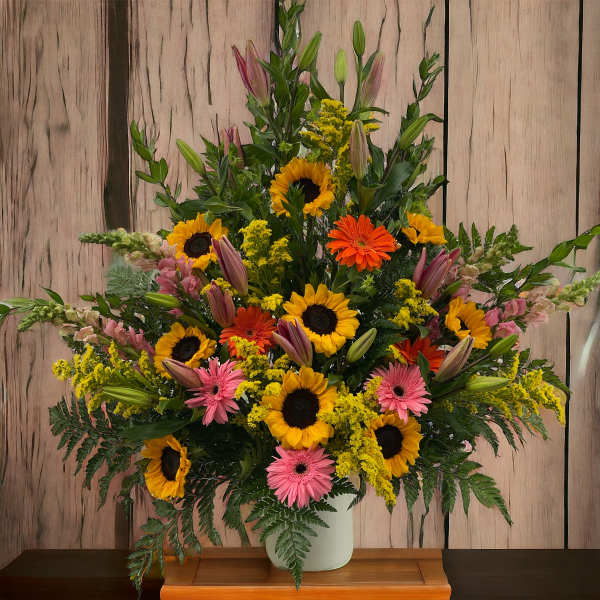 Tall mixed bouquet with sunflowers, pink gerberas, and yellow filler in a vase