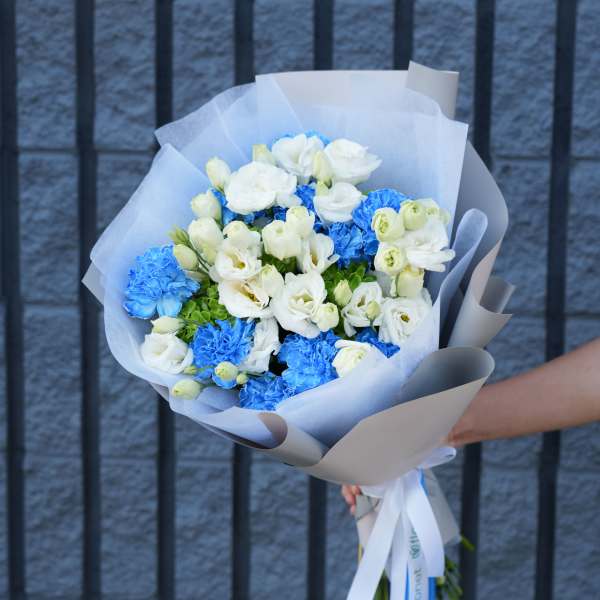 Bouquet of white and bright blue flowers wrapped in paper