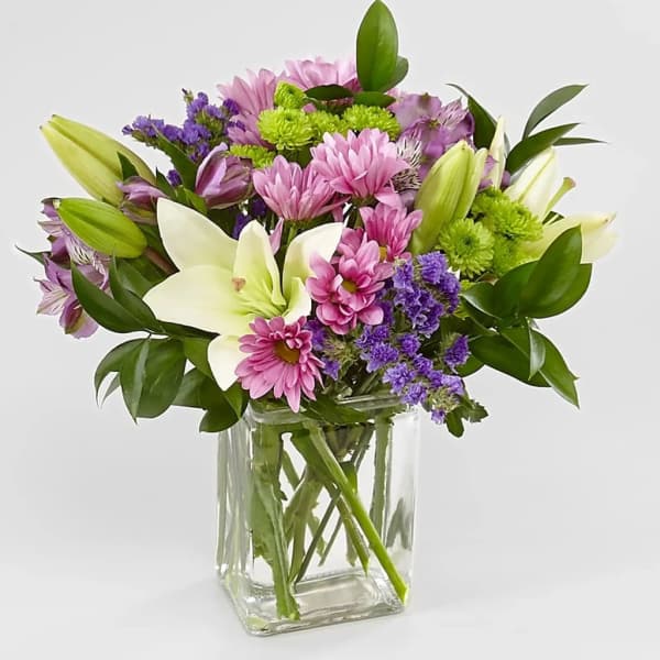 Mixed bouquet of pink and purple flowers in a clear glass vase
