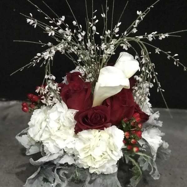 Red roses and white calla lilies in a white container with white filler flowers