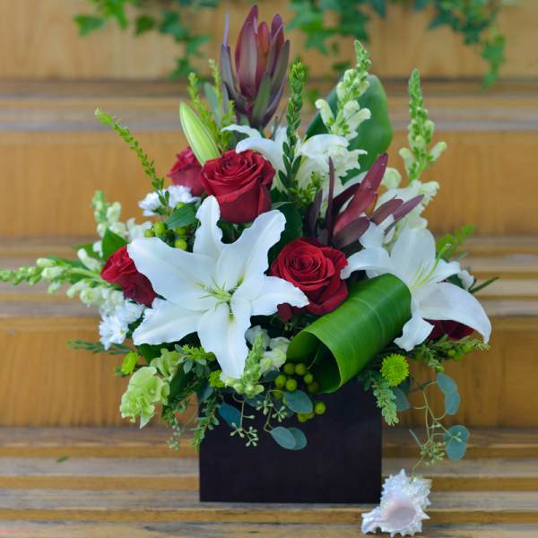 Bouquet of red roses and white lilies in a black box