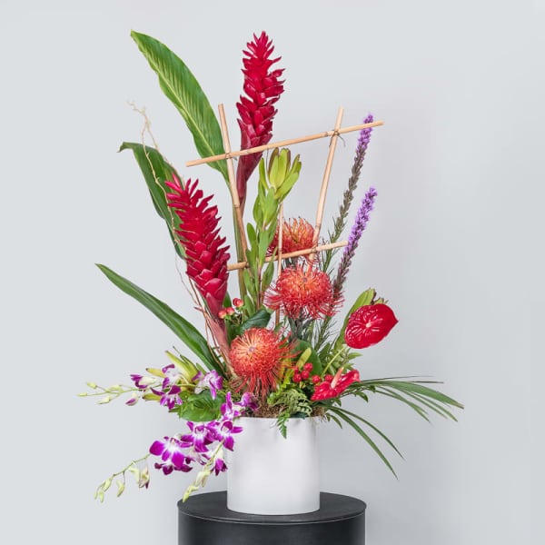 Tropical flower arrangement in a white cylindrical vase