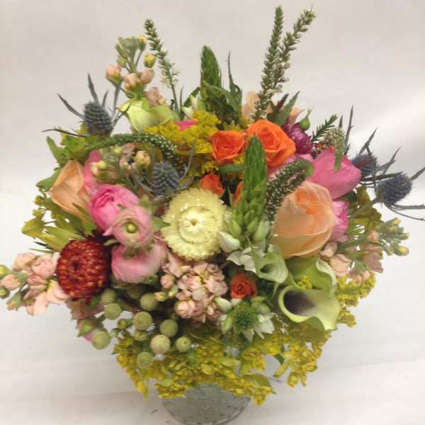 Mixed bouquet in a gray vase with pink, orange, yellow, and green blooms