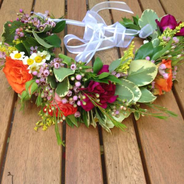 Floral crown with orange and pink roses and a white ribbon tie