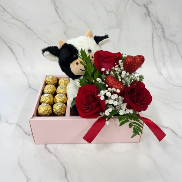 Red roses with chocolates and a plush cow in a pink gift box