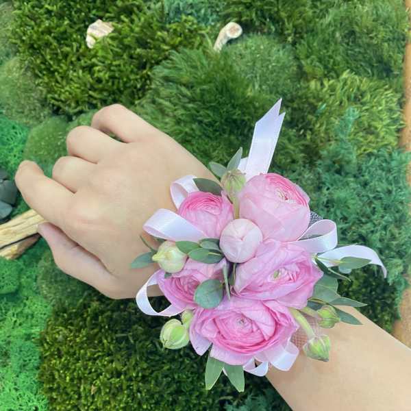Pink floral wrist corsage with ribbon on a person's wrist