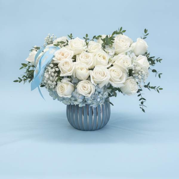 White rose bouquet in a silver vase with a blue ribbon