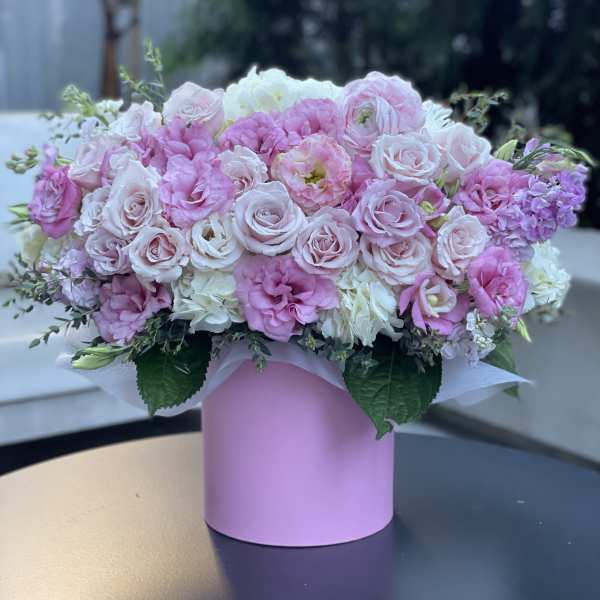 Pink and white roses arranged in a pastel pink box