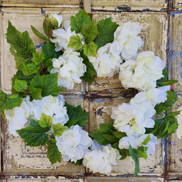 White hydrangea wreath with green leaves on a rustic background