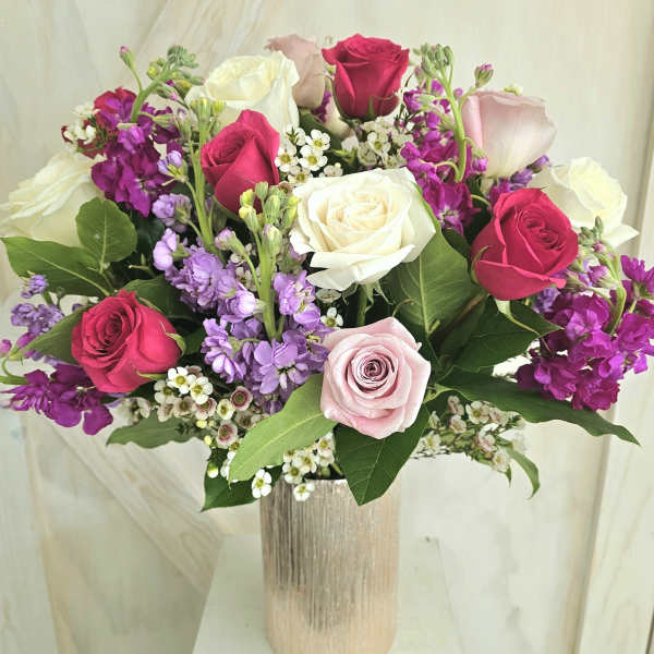 Bouquet of pink, white, and purple roses in a tall vase