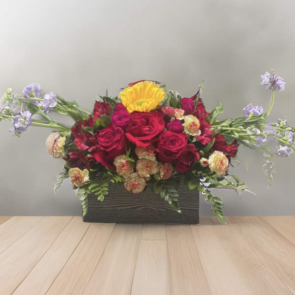 Red roses and a yellow bloom in a rectangular box with lavender accents