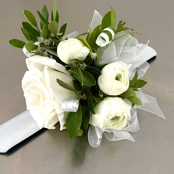 White rose and ranunculus bouquet with green foliage and white ribbon