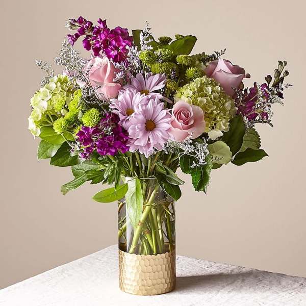 Mixed pink and purple flowers arranged in a clear glass vase