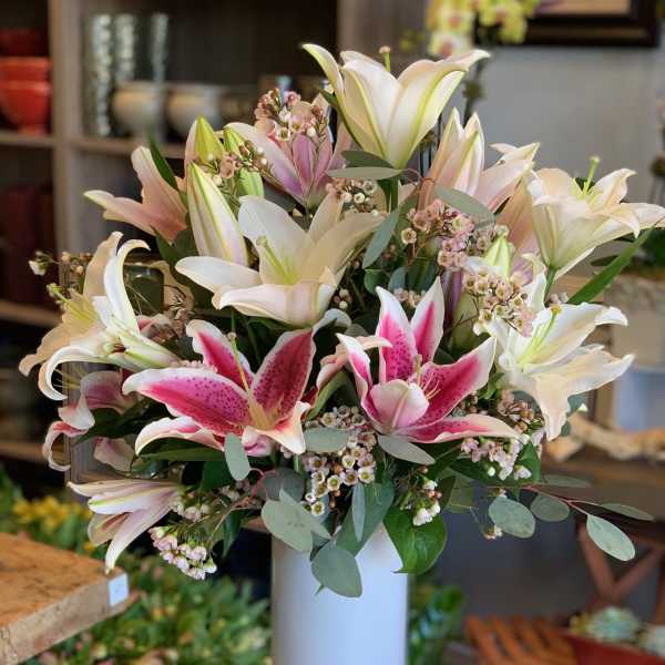 Bouquet of pink and white lilies in a tall white vase