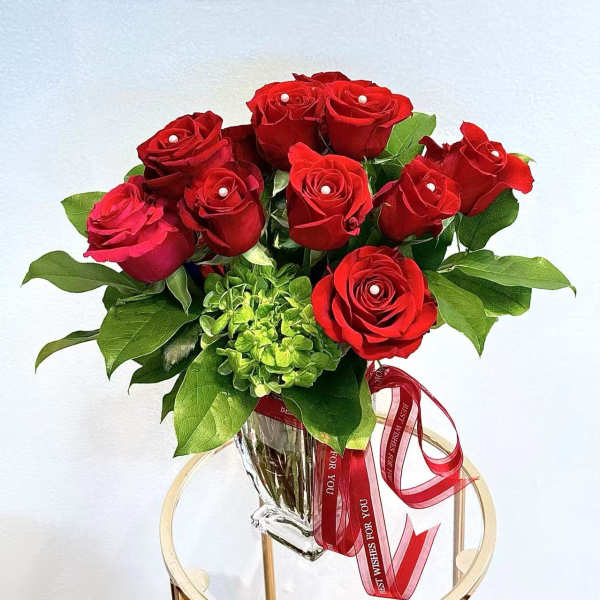Red roses arranged in a clear glass vase with a red ribbon.