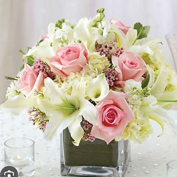 Pink roses and white lilies arranged in a square glass vase