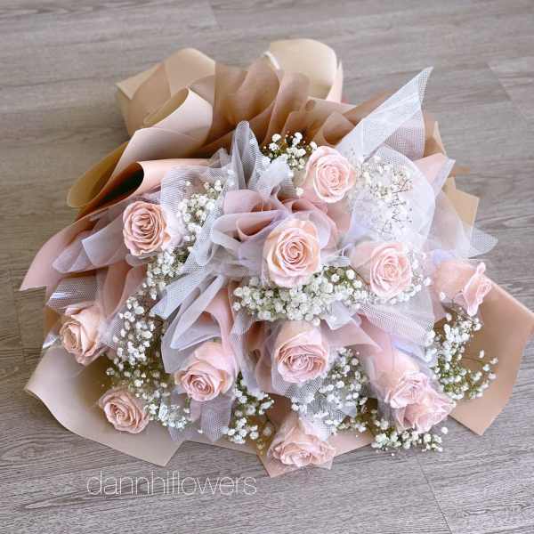 Bouquet of pale pink roses with white baby's breath in blush and beige wrap