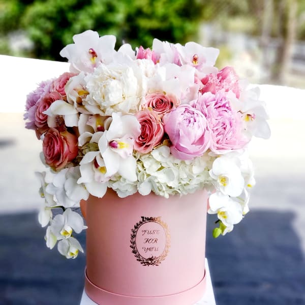 Pink and white flower arrangement in a round pink box