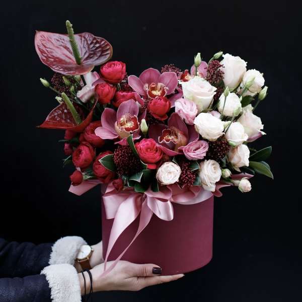 Pink and white floral arrangement in a round box with ribbon