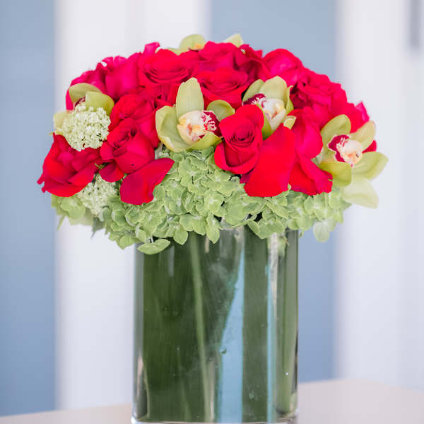 Bouquet of hot pink roses and green orchids in a glass vase