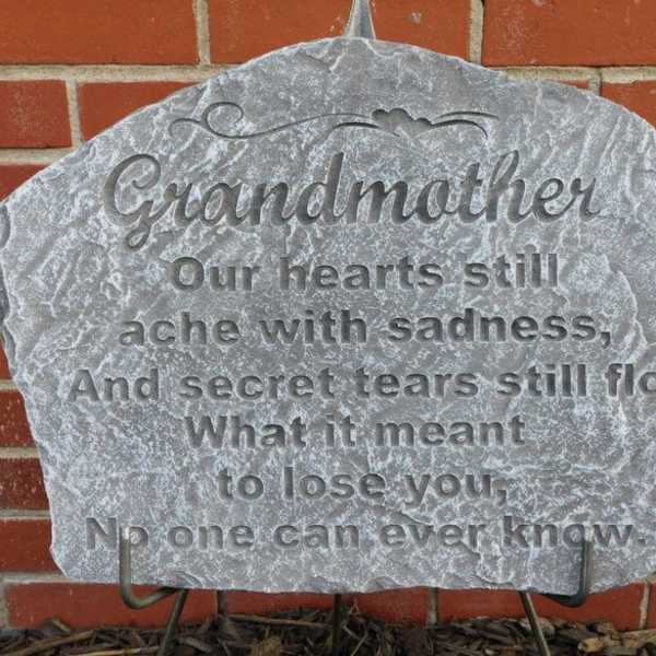 Gray memorial stone engraved for grandmother against a brick wall