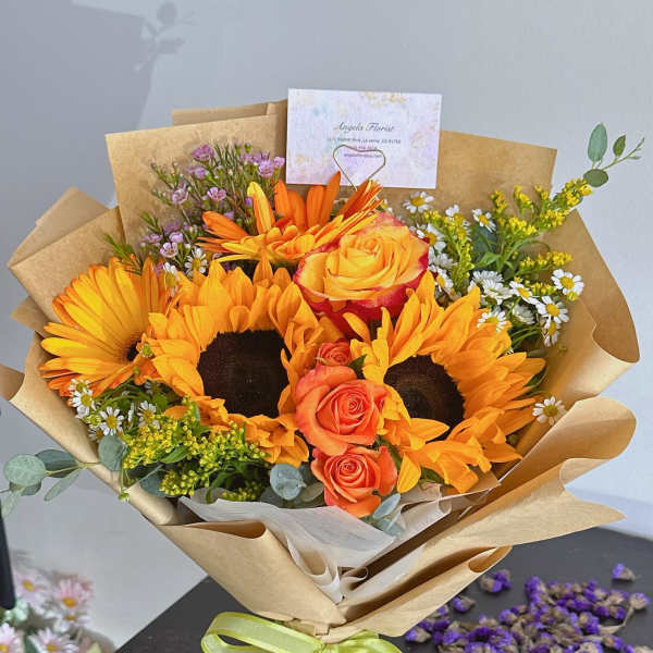 Bouquet of sunflowers and orange roses wrapped in kraft paper