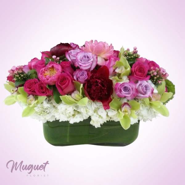 Pink and lavender flower arrangement in a green container