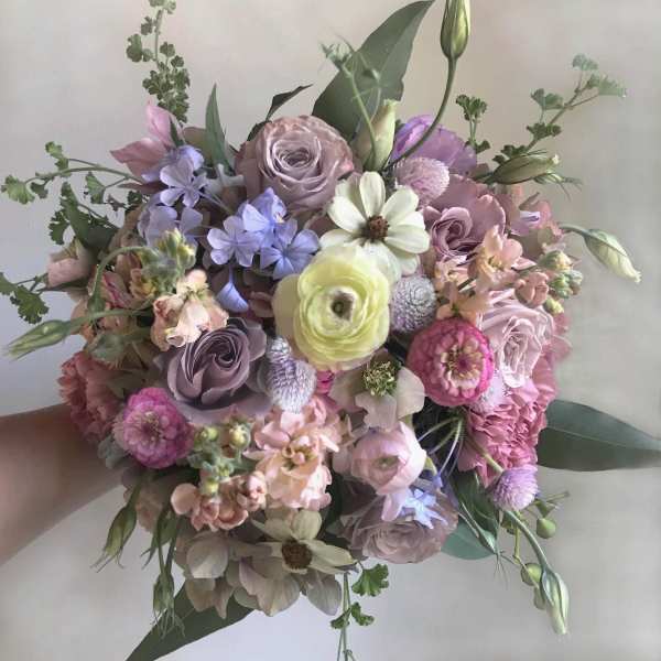 Handheld bouquet of pastel flowers in pink, lavender, and cream