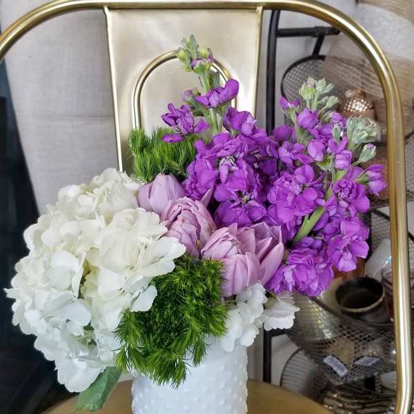 Purple and white flowers arranged in a white textured vase