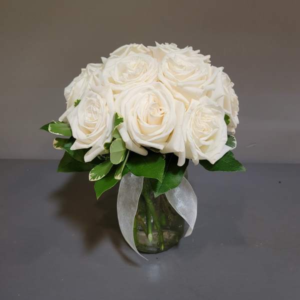 White rose bouquet in a glass vase with a sheer ribbon