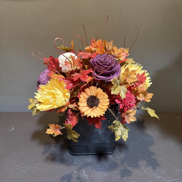 Autumn floral arrangement in a black container with colorful flowers and leaves