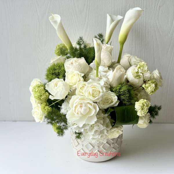 White roses and calla lilies arranged in a patterned vase
