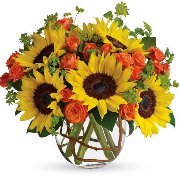 Low glass vase of bright yellow sunflowers and orange roses in a compact mixed arrangement