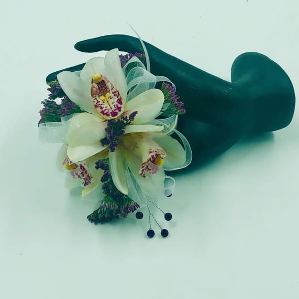 White orchid corsage with purple accents on a dark wristlet