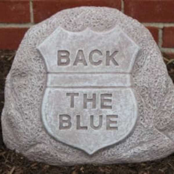 A stone sign shaped like a police badge with the words "BACK THE BLUE."
