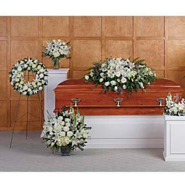 White funeral floral arrangements around a wooden casket