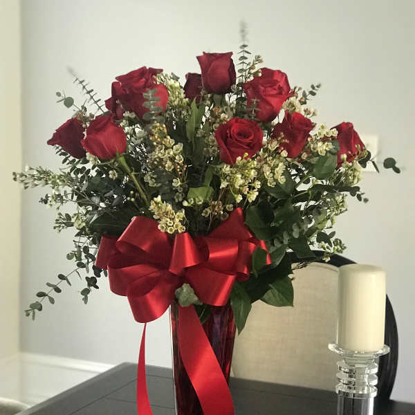 Red roses in a tall vase with a large red ribbon