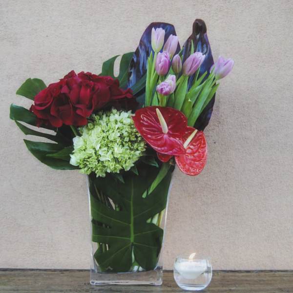 Mixed floral arrangement in a clear vase with red and pink blooms