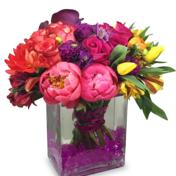 Colorful bouquet of mixed flowers in a square glass vase