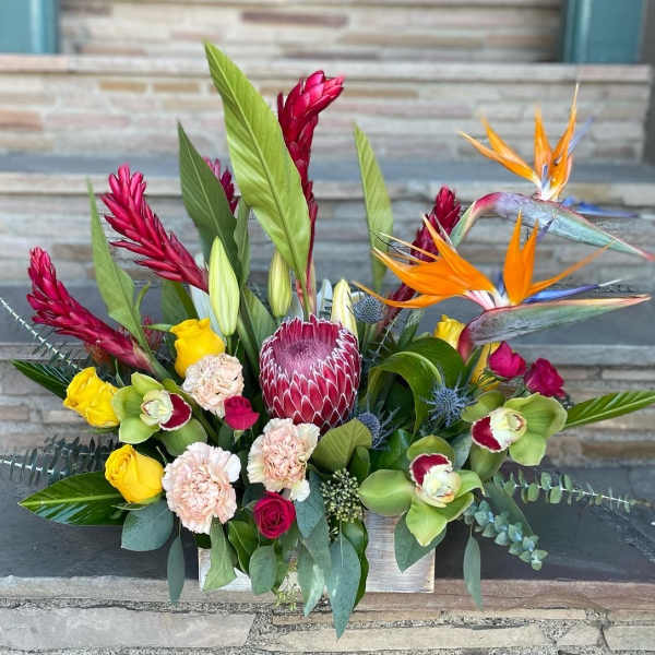 Tropical flower arrangement with birds of paradise and roses in a rectangular container